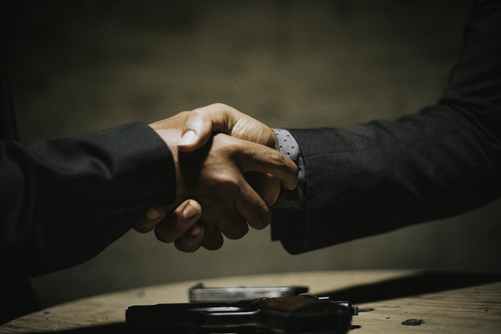 Two professionals shaking hands across a table after a business strategy meeting
